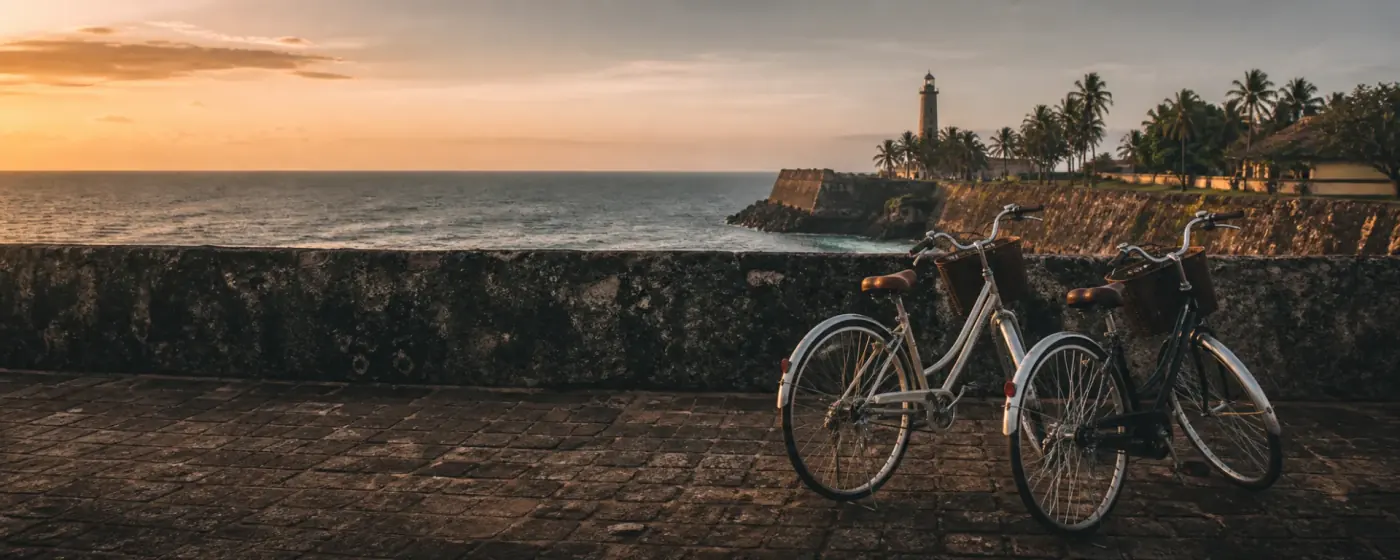 Step-through bicycles parked on the Galle Fort ramparts at sunset.